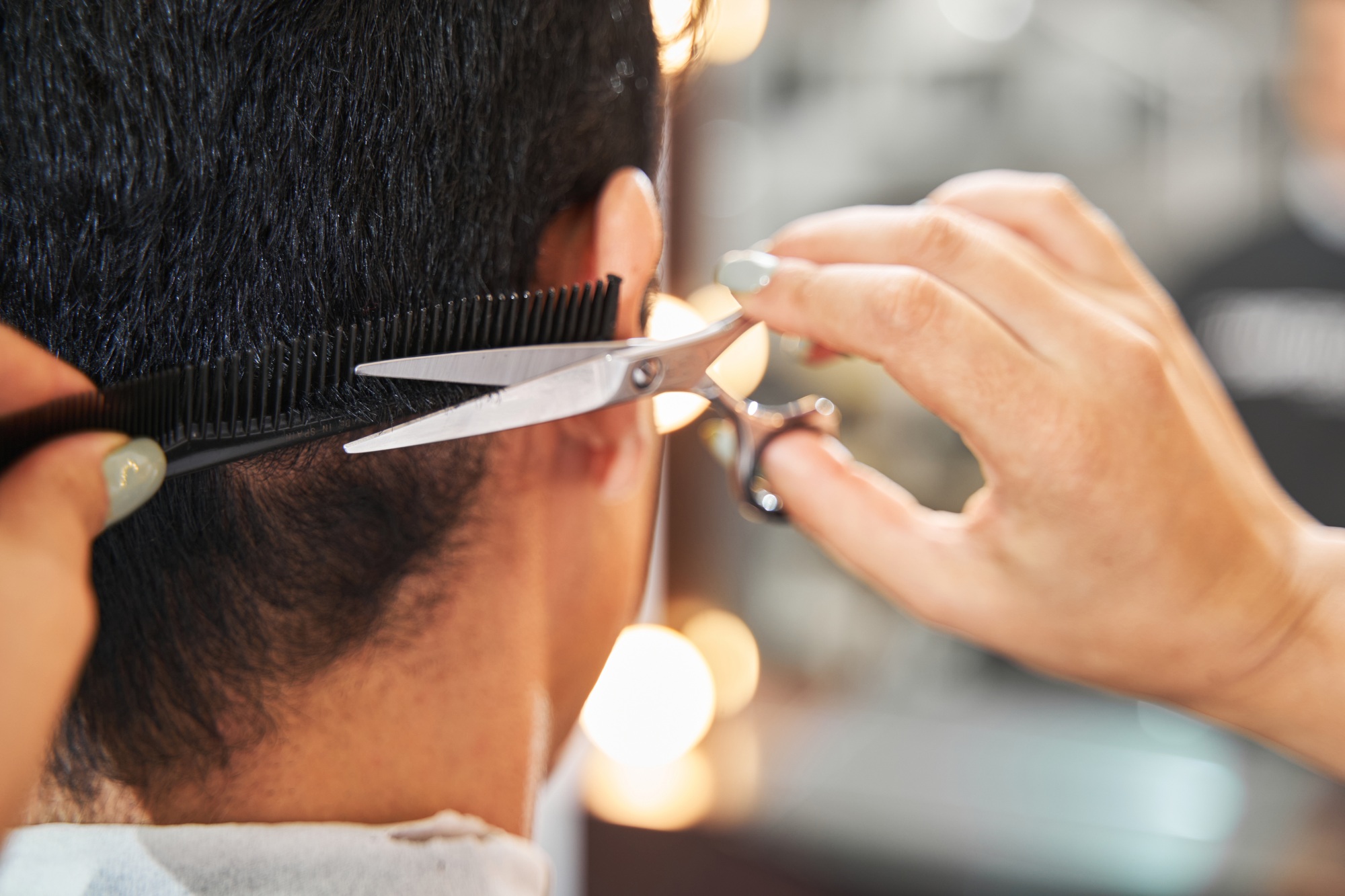 Person doing haircut to client with scissors